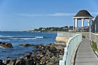 Newport Cliff Walk paved path bordering luxury Gilded Age mansions and crashing ocean waves